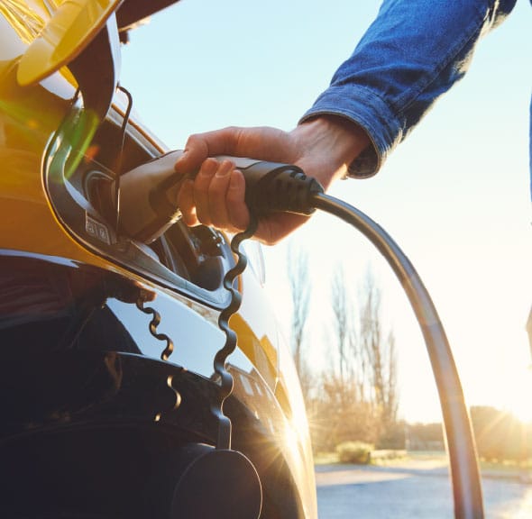 A photograph of someone plugging a charger into their electric car